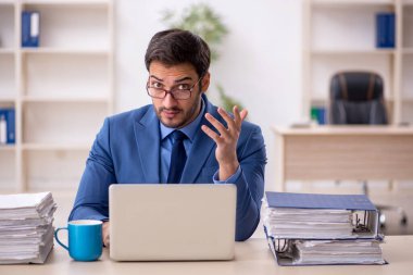 Genç işadamı ve işyerinde çok fazla iş var.