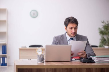 Genç erkek çalışan işyerinde oturuyor.