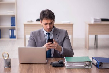 Genç erkek çalışan işyerinde oturuyor.