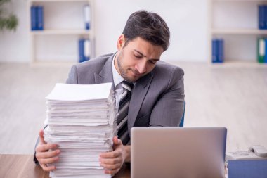 Genç bir çalışan ve ofiste çok fazla iş var.