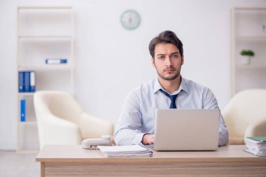 Genç işadamı işyerinde oturuyor.