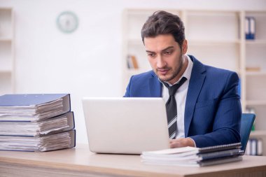 Genç işadamı ve işyerinde çok fazla iş var.