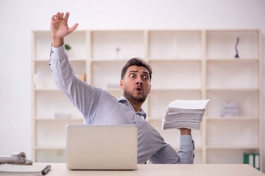 Genç erkek çalışan işyerinde oturuyor.