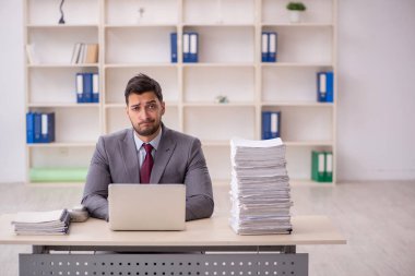 Young employee and too much work at workplace