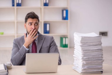 Young employee and too much work at workplace