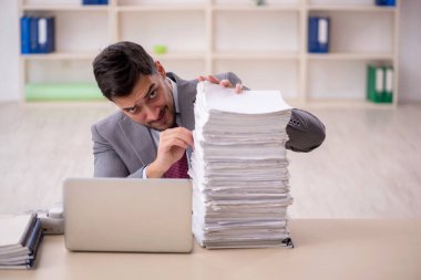 Young employee and too much work at workplace