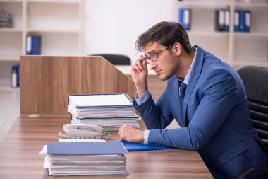 Genç bir erkek işçi ve işyerinde çok fazla iş var.