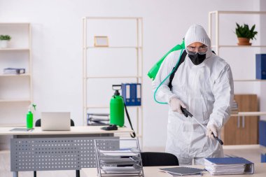 Young contractor disinfecting office during pandemic