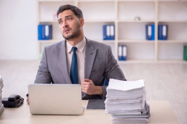 Young employee and too much work at workplace