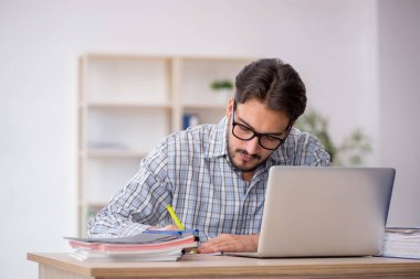 Genç erkek çalışan işyerinde oturuyor.