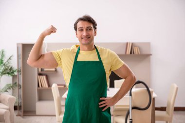 Genç adam evi temizliyor.