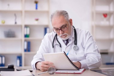 Klinikte çalışan yaşlı bir doktor.