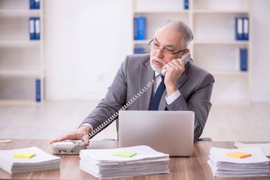 Old businessman employee unhappy with excessive work at workplace