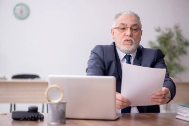 Old employee sitting at workplace