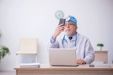 Old docror otolaryngologist working at the hospital