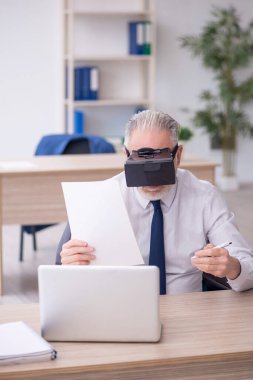 Old businessman employee wearing virtual glasses in the office
