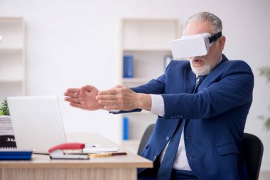 Old businessman employee wearing virtual glasses in the office