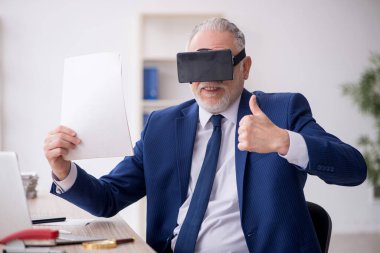 Old businessman employee wearing virtual glasses in the office