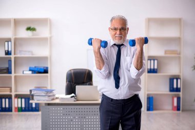 Eski erkek çalışanın teneffüste spor egzersizleri yapıyor.