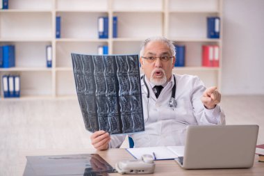 Klinikte çalışan yaşlı erkek radyoloji uzmanı.