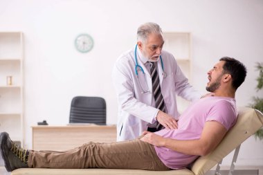 Genç hasta yaşlı doktoru ziyaret ediyor.