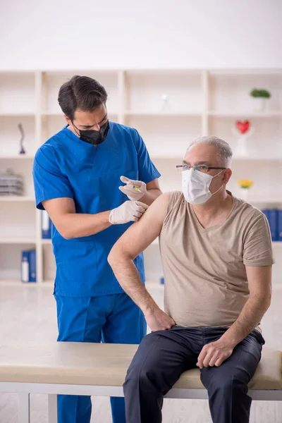 Old patient visiting young male doctor in vaccination concept
