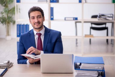 Genç işadamı ofiste kitap okuyor.