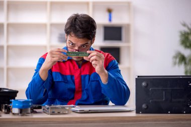 Atölyede bilgisayar tamir eden genç bir tamirci.