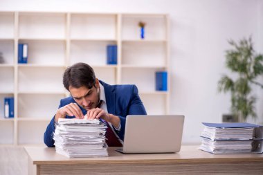 Genç işadamı ve işyerinde çok fazla iş var.