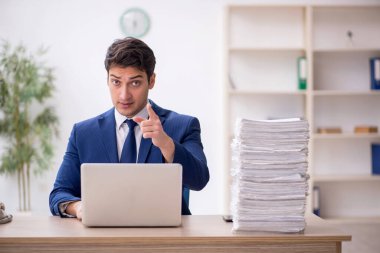 Young employee and too much work at workplace