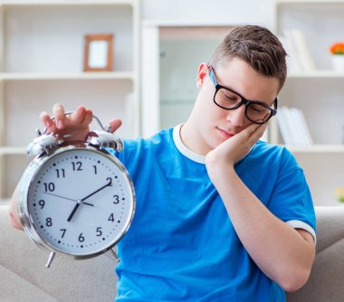 Sınavlara hazırlanan genç öğrenci evde bir kanepede ders çalışıyor.