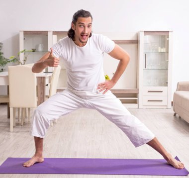 Genç adam evde fiziksel egzersiz yapıyor.