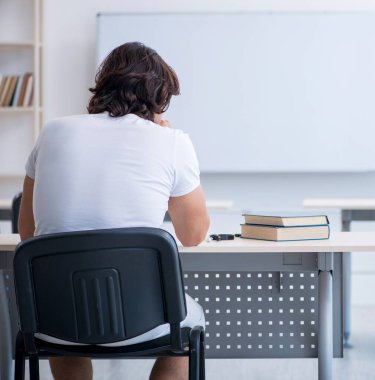 Beyaz tahtanın önündeki genç erkek öğrenci.