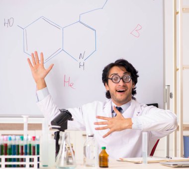 Beyaz panonun önündeki komik genç kimyager.