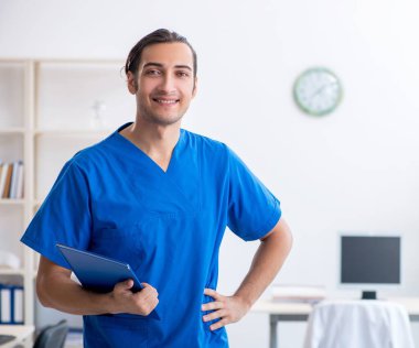 Klinikte çalışan genç erkek doktor.