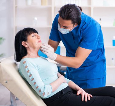 Yaşlı kadın estetik ameliyat için erkek doktoru ziyaret ediyor.