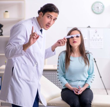 Erkek doktor göz doktorunu ziyaret eden genç kadın.