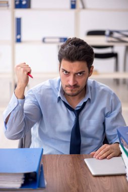 Young employee and too much work at workplace