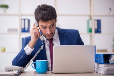 Young businessman employee speaking by phone at workplace