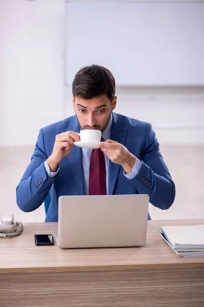 Stock image Young employee drinking coffee at workplace