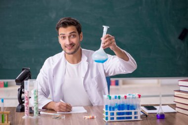 Young chemist in front of green board