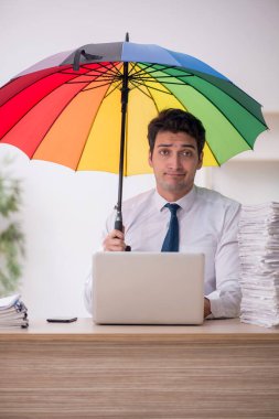 Young employee holding an umbrella at workplace