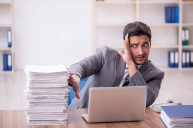 Genç bir çalışan ve ofiste çok fazla iş var.