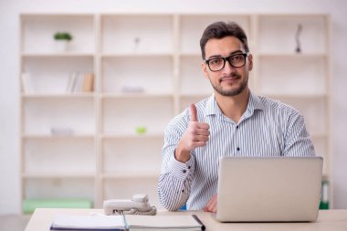 Genç erkek çalışan işyerinde oturuyor.