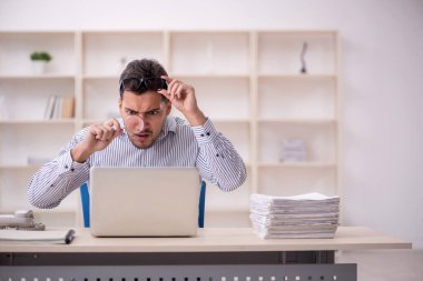 Genç erkek çalışan işyerinde oturuyor.