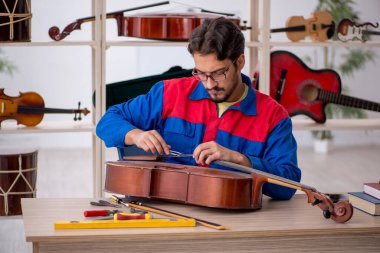 İçeride müzik aletlerini tamir eden genç bir adam.