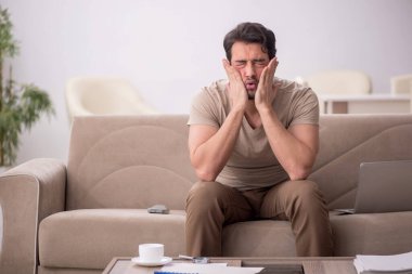 Genç erkek çalışan salgın sırasında evden çalışıyor.