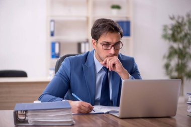 Genç bir erkek işçi ve işyerinde çok fazla iş var.