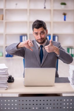 Young employee and too much work at workplace