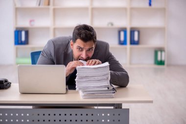 Young employee and too much work at workplace